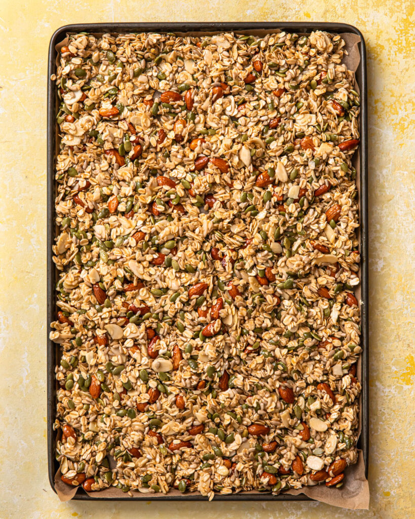 Lemon blueberry granola mixture spread out on a baking tray.