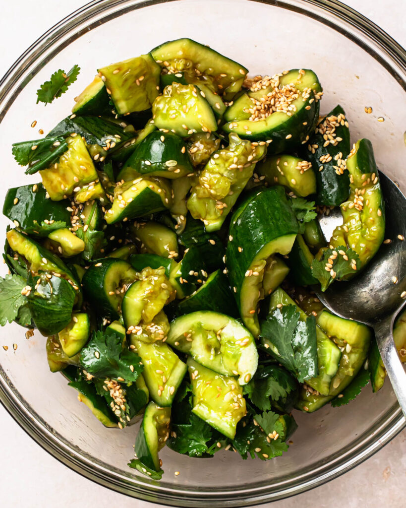 Smashed sesame cucumber salad mixed together in a glass bowl. 