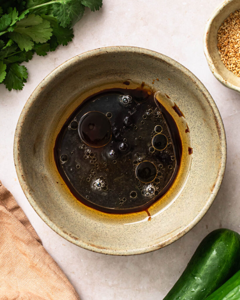 Dressing ingredients for sesame cucumber salad added to a bowl. 