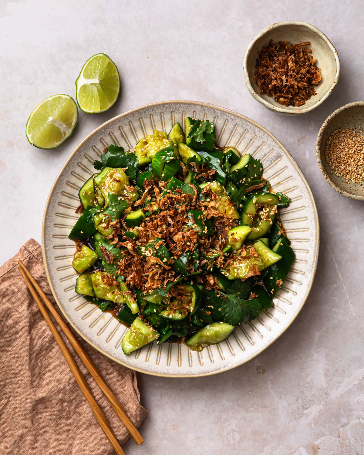 Smashed Sesame Cucumber Salad on a serving plate, topped with fried onions.
