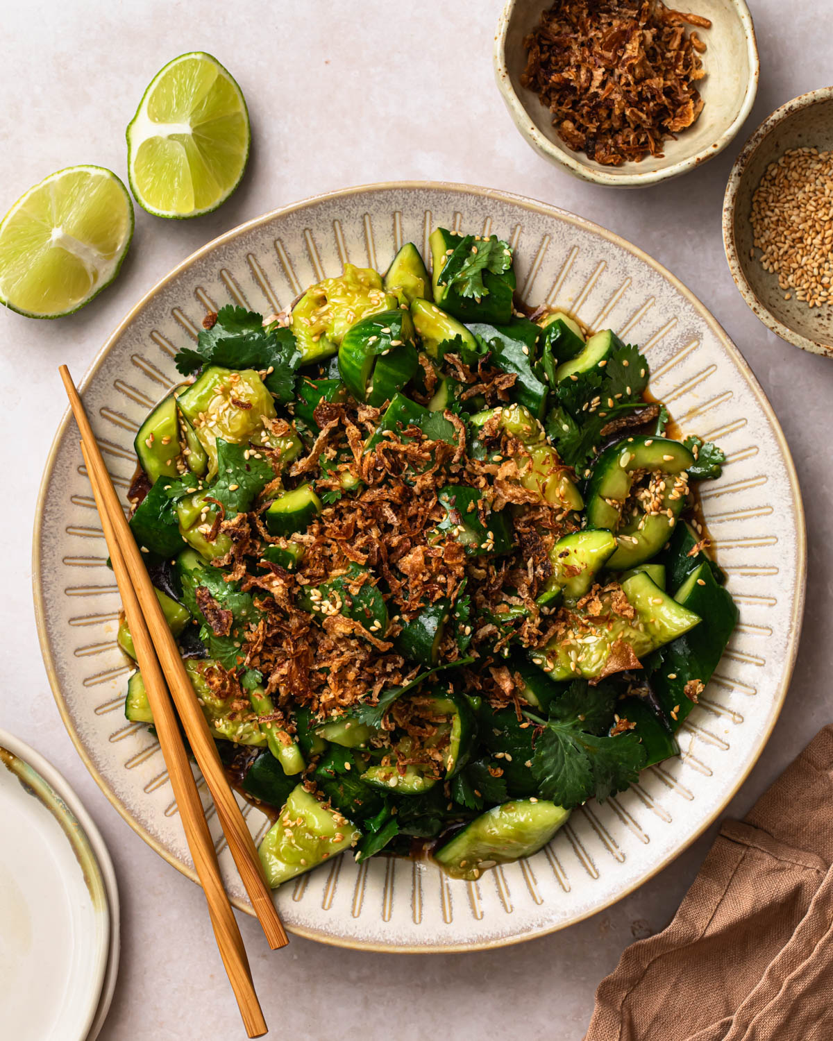 Smashed Sesame Cucumber Salad on a serving plate, topped with fried onions. 