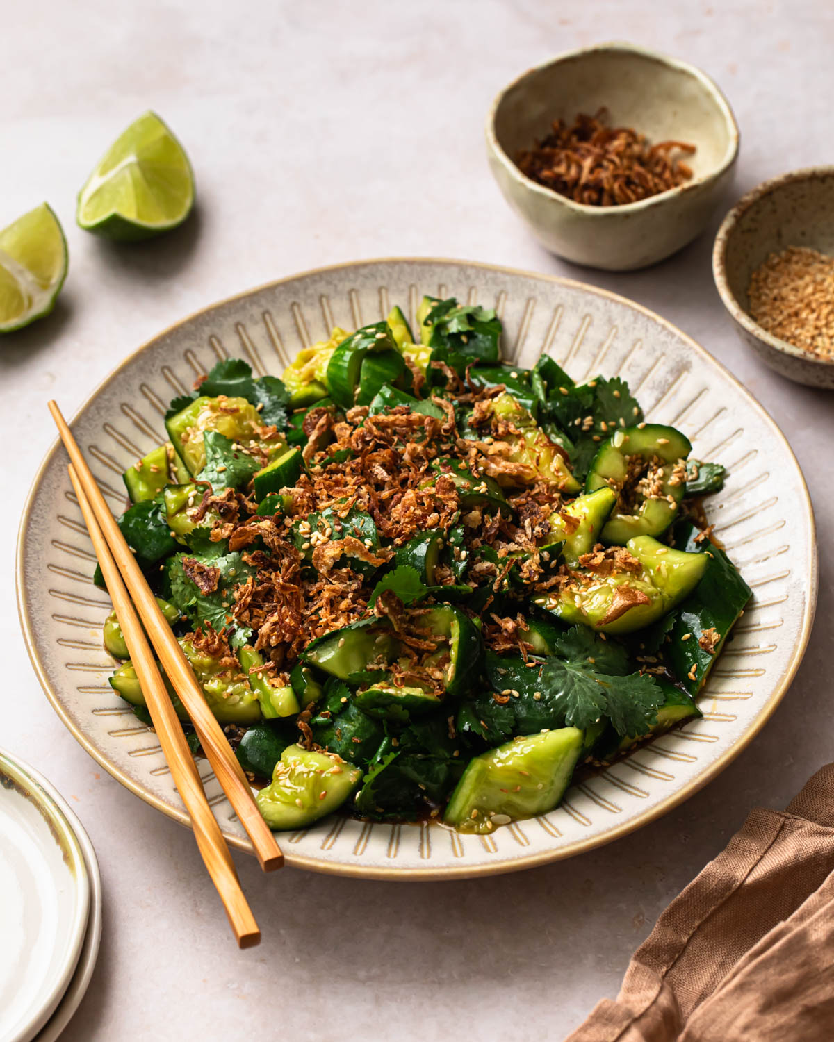 Smashed Sesame Cucumber Salad on a serving plate, topped with fried onions.