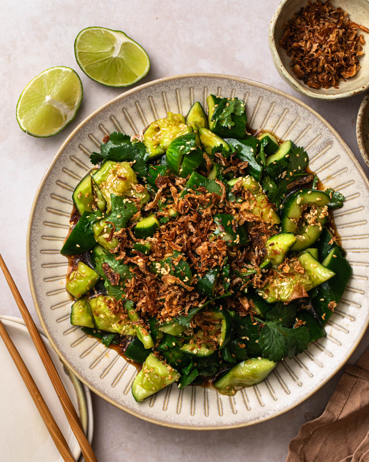 Smashed Sesame Cucumber Salad on a serving plate, topped with fried onions.
