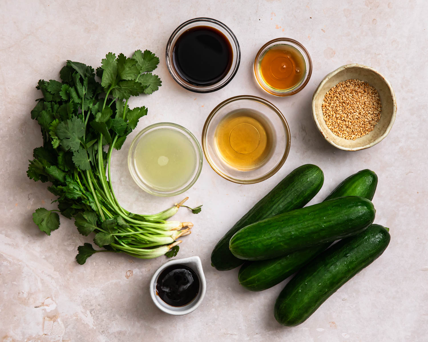 Ingredients for sesame cucumber salad laid out in individual bowls. 