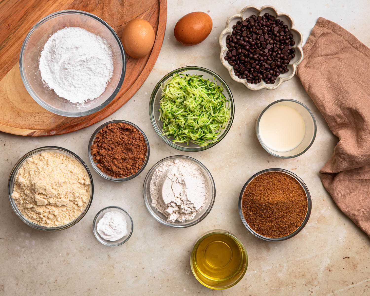 Ingredients for gluten free chocolate zucchini muffins laid out in individual bowls. 