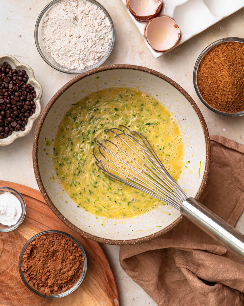 Wet ingredients for gluten free chocolate zucchini muffins mixed together in a bowl. 