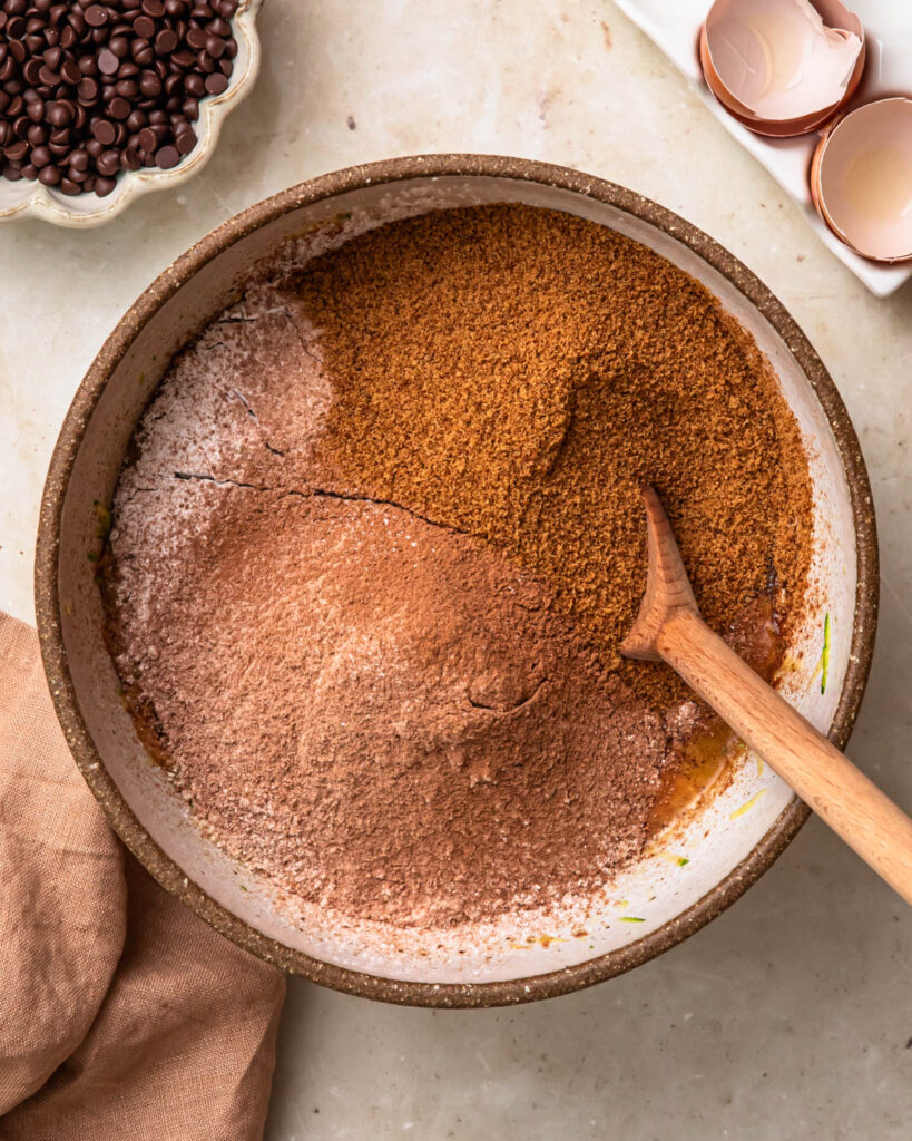 Dry ingredients added to wet ingredients to make gluten free chocolate zucchini muffins. 