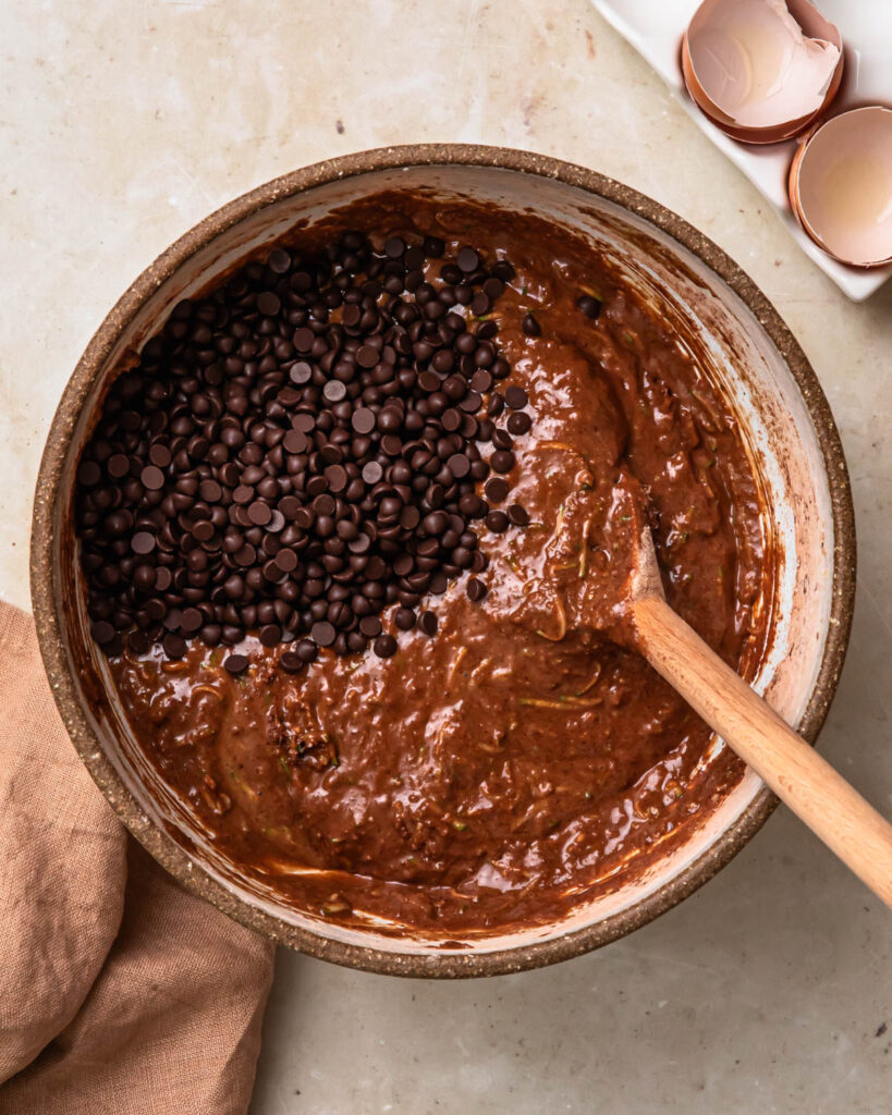 Chocolate chips added to  muffin batter in a bowl. 