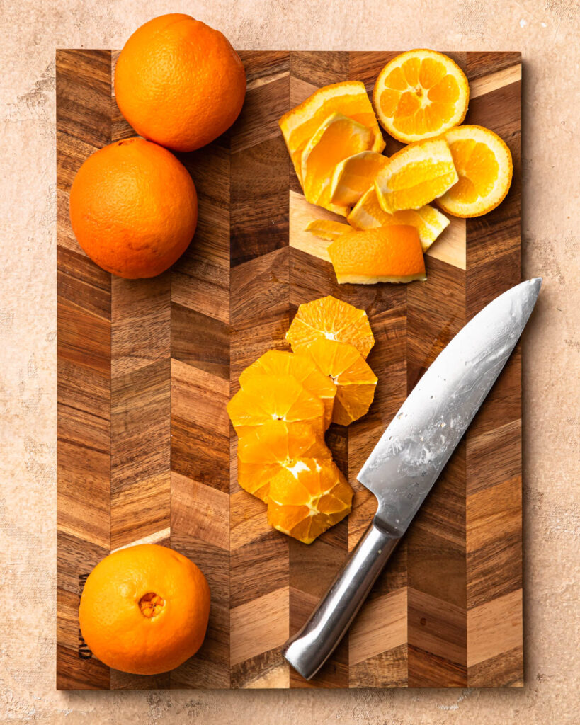 An orange cut into slices on a cutting board. 