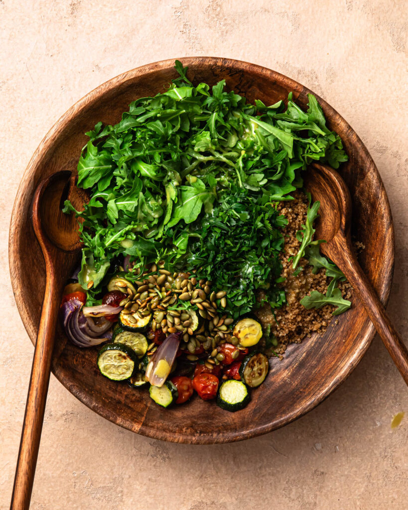 Ingredients for roasted zucchini and quinoa salad added to a large salad bowl. 