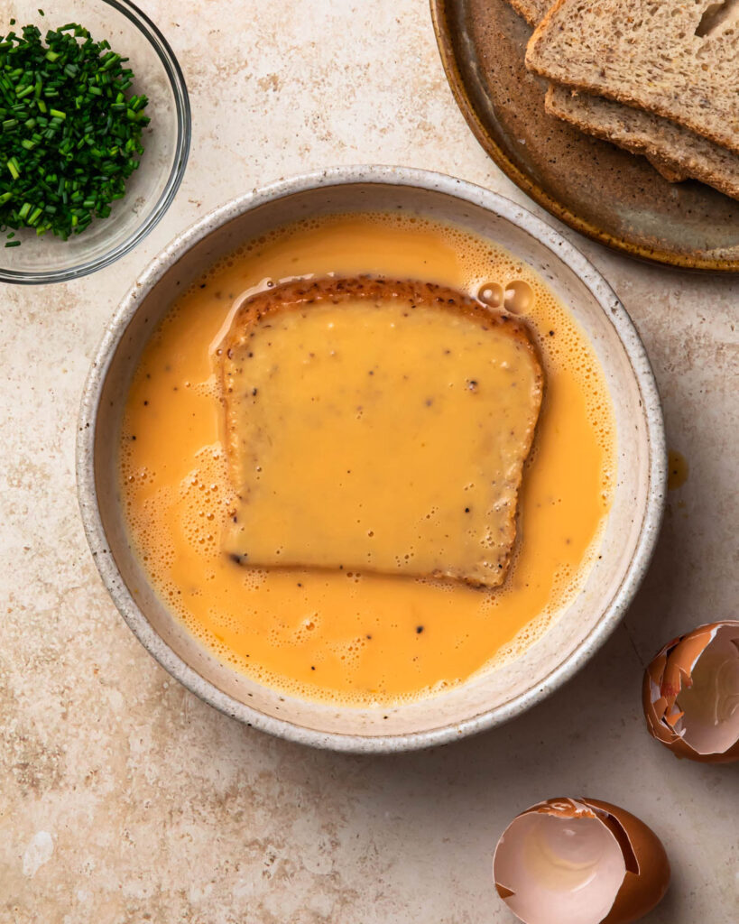 Bread placed into egg mixture to make savoury French toast.