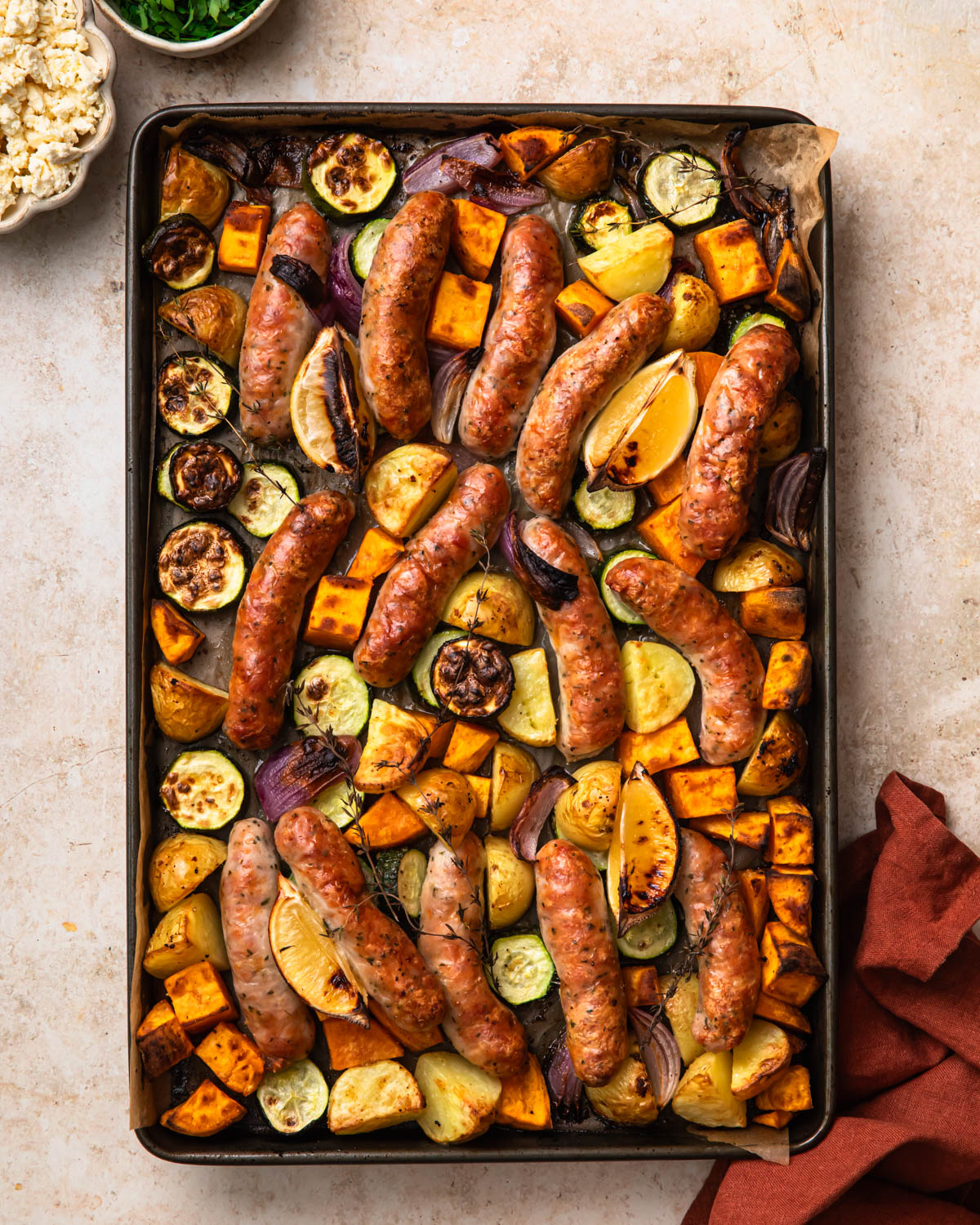 Cooked chicken sausage and vegetables on a sheet pan.
