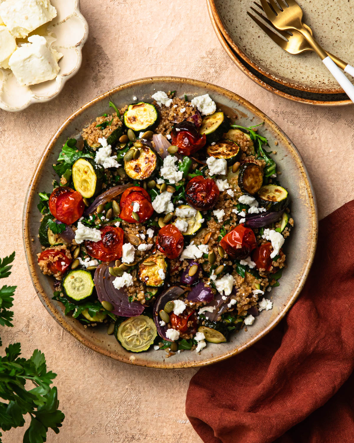 Roasted zucchini quinoa salad in a bowl, topped with goats cheese.