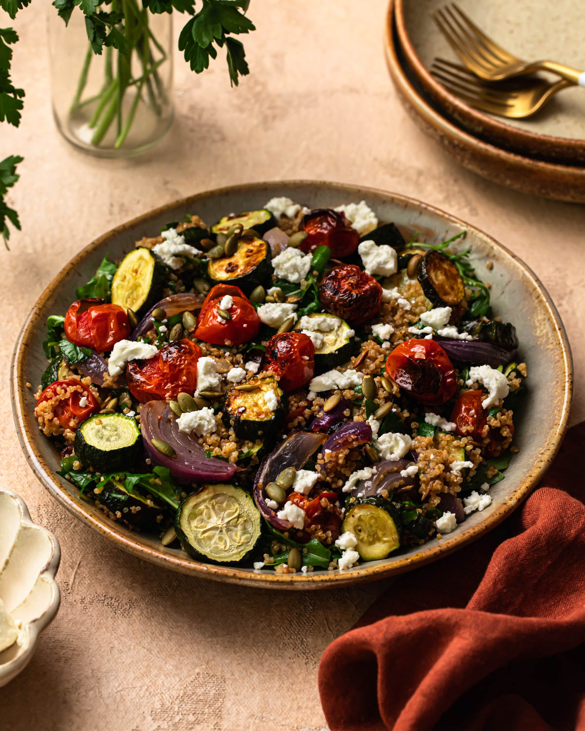 Front on photo of roasted zucchini quinoa salad in a bowl, topped with goats cheese.