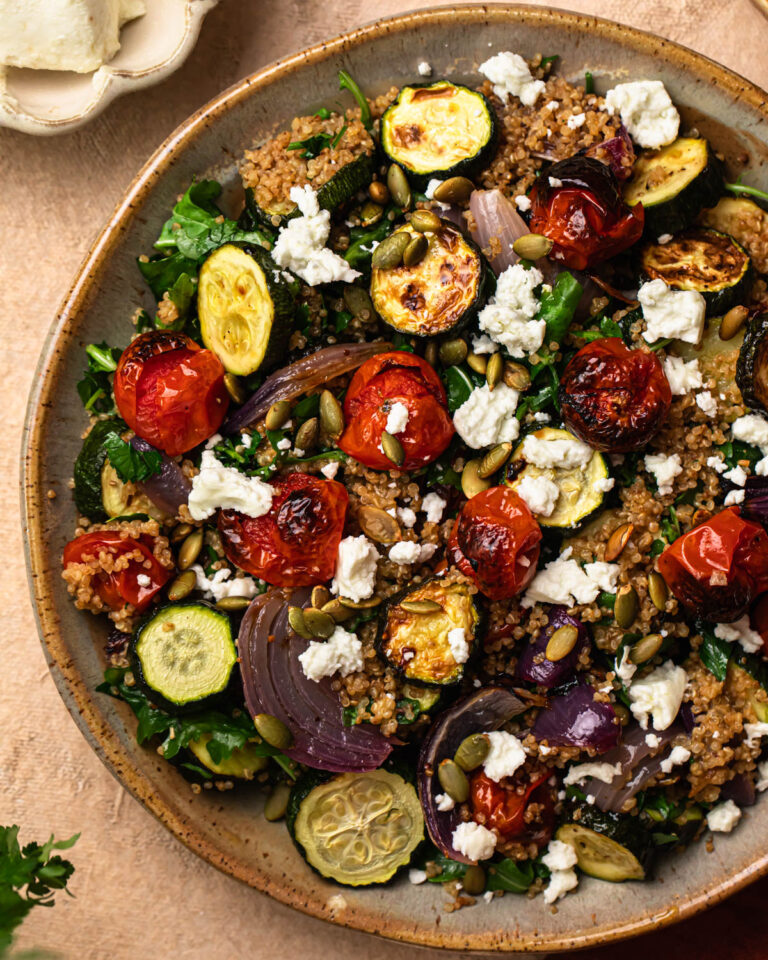 Roasted zucchini quinoa salad in a bowl, topped with goats cheese.