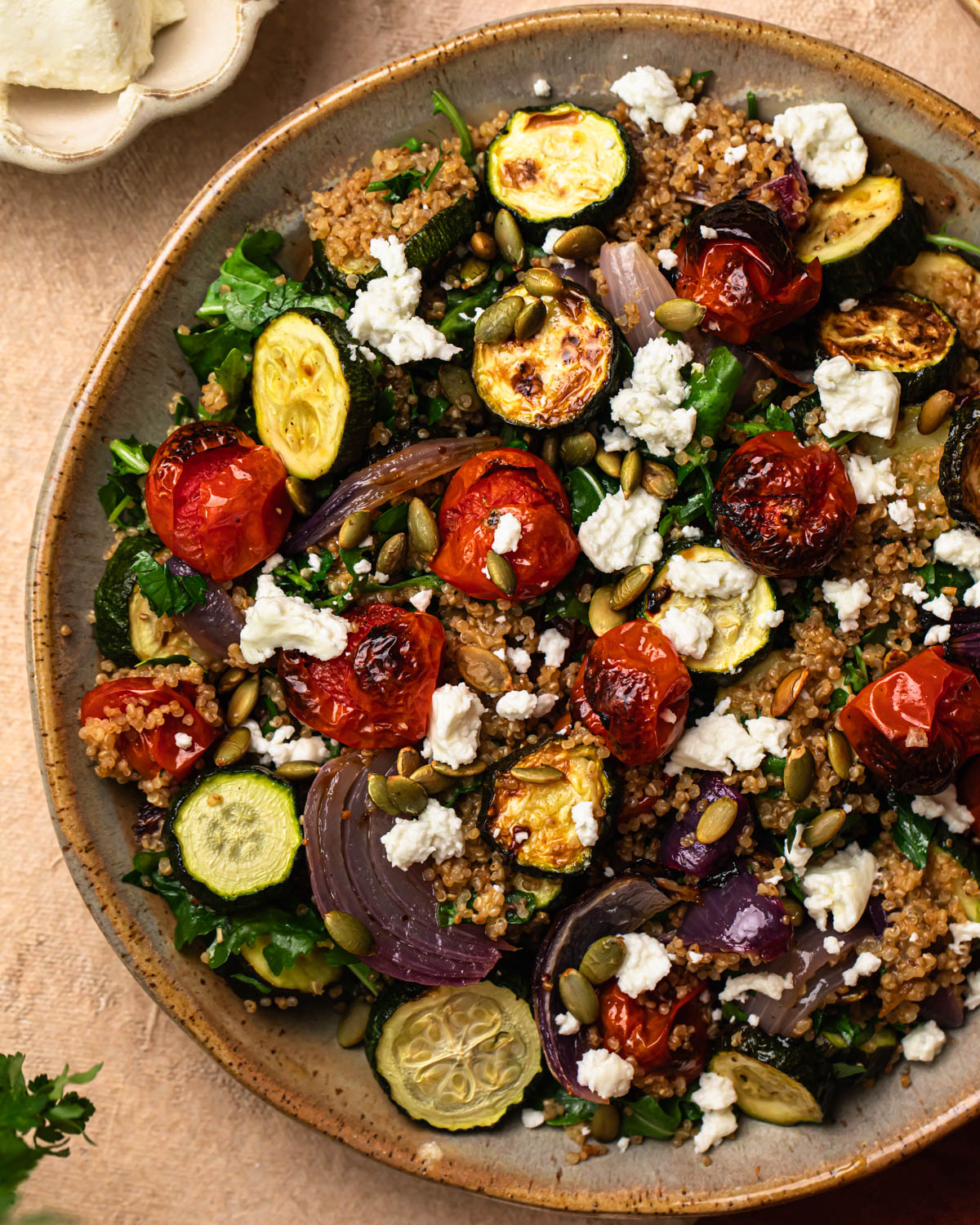 Roasted zucchini quinoa salad in a bowl, topped with goats cheese.
