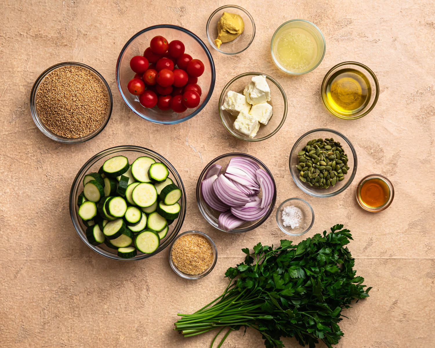 Ingredients for roasted zucchini quinoa salad laid out in individual bowls. 