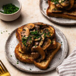 Savoury French Toast on a plate topped with miso butter mushrooms and chopped chives.