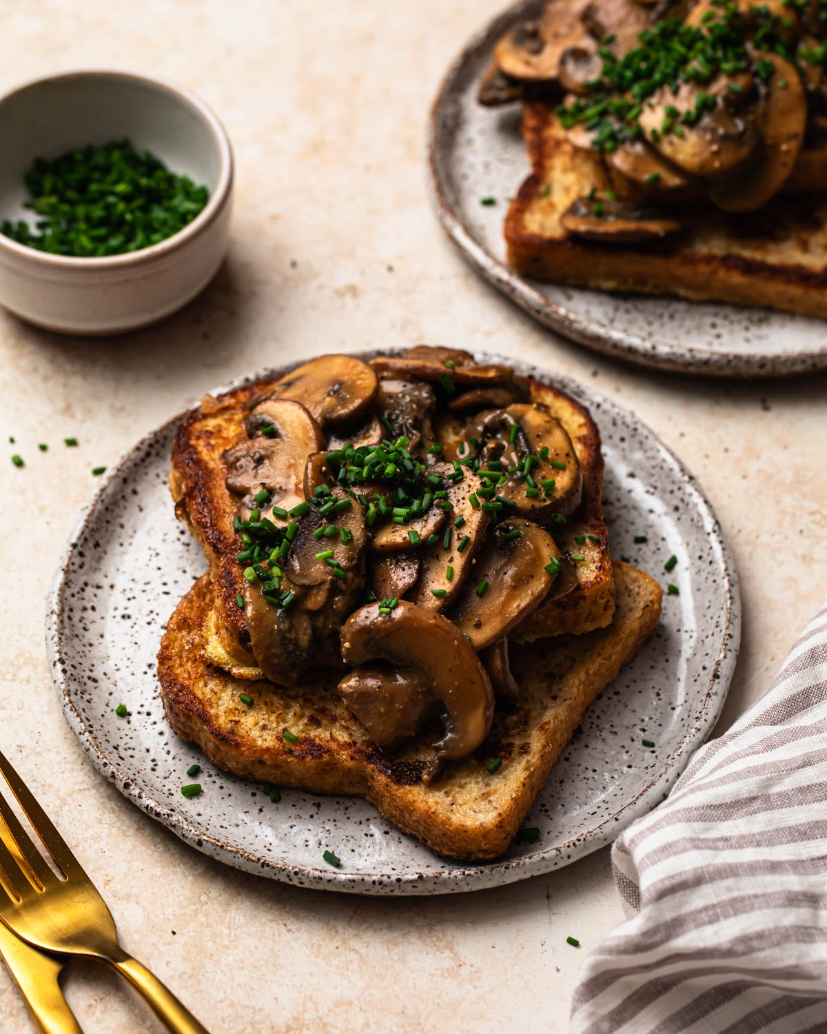 Savoury French Toast on a plate topped with miso butter mushrooms and chopped chives.