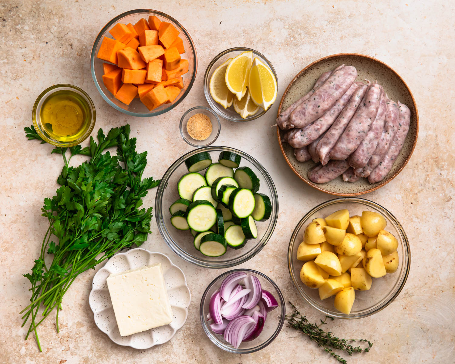 Ingredients for sheet pan chicken sausage and vegetables laid out in individual bowls. 