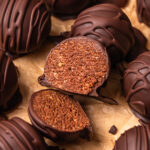 Close up photo of a double chocolate protein ball sliced in half, showing the cake like centre.