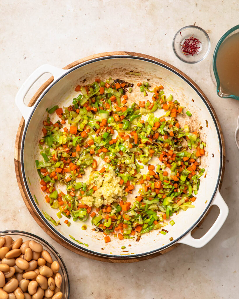 Aromatics sautéing in a pan to make brothy beans.