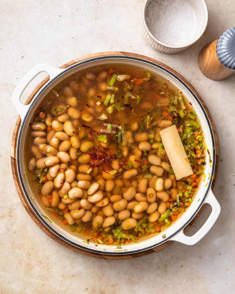 All ingredients to make Brothy beans added to a pan.