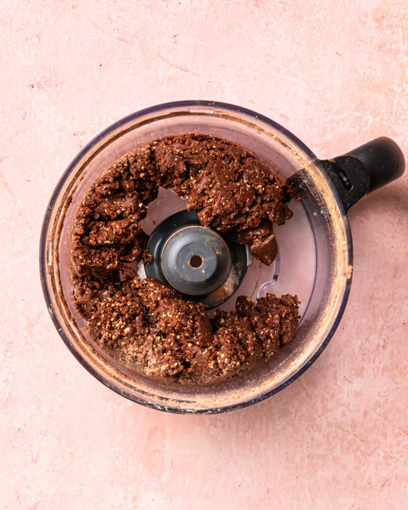 No bake protein balls mixture blended together in the drum of a food processor.