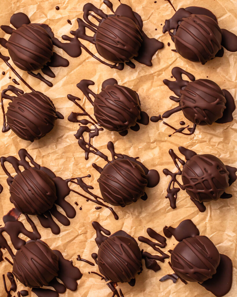 Close up of the finished double chocolate protein balls lined up on baking paper. 