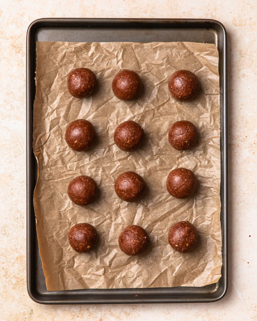 Chocolate protein balls on a baking paper lined tray.