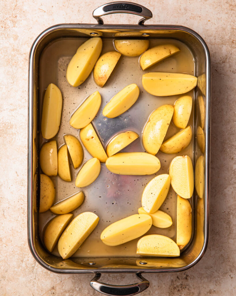 Potatoes in a roasting pan with chicken stock and lemon juice. 