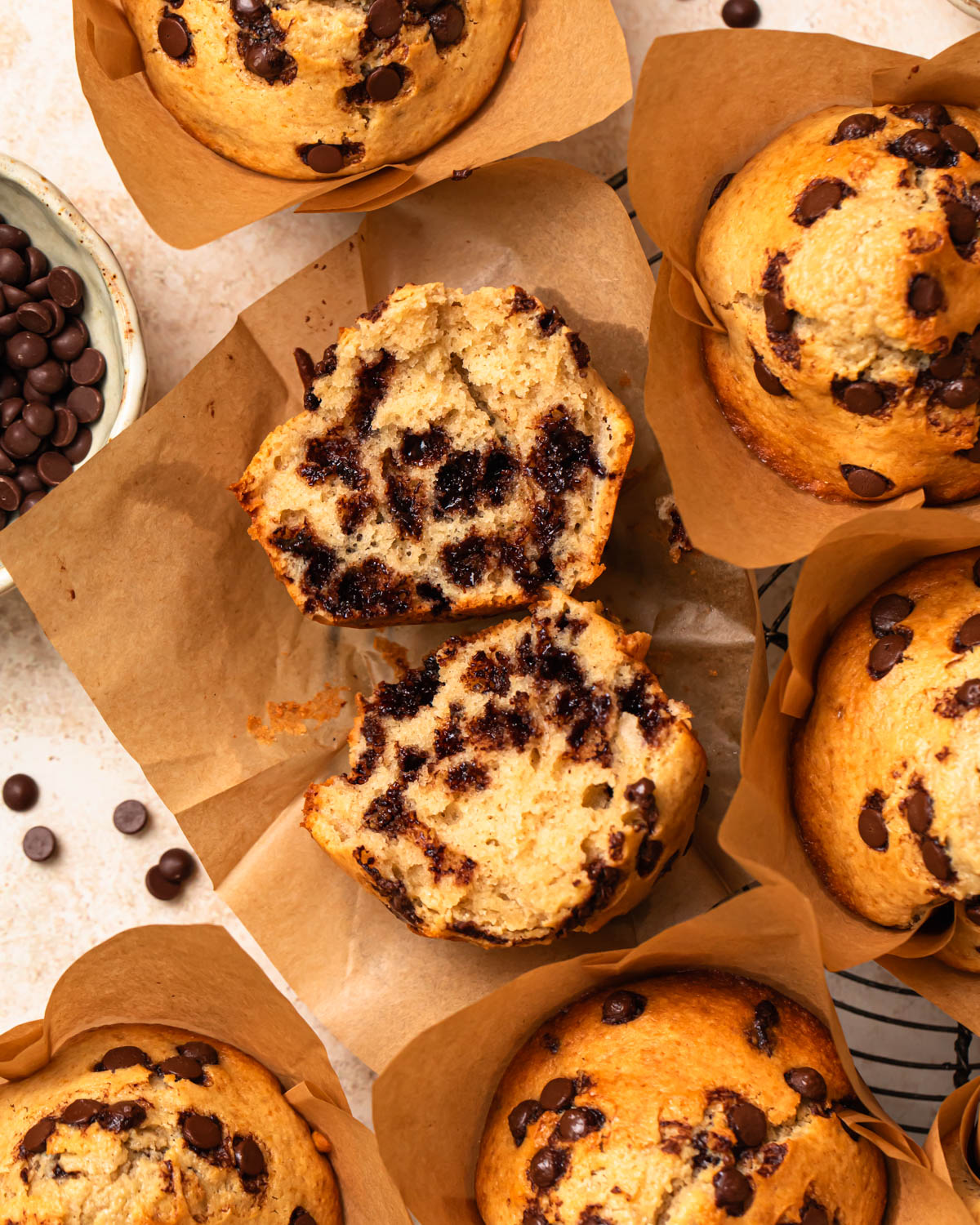Close up photo of protein choc chip muffins, with one muffin broken in half to reveal the inside.