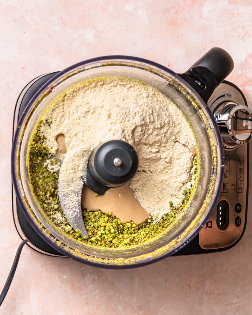 Ingredients for pistachio protein balls added to the drum of a food processor. 