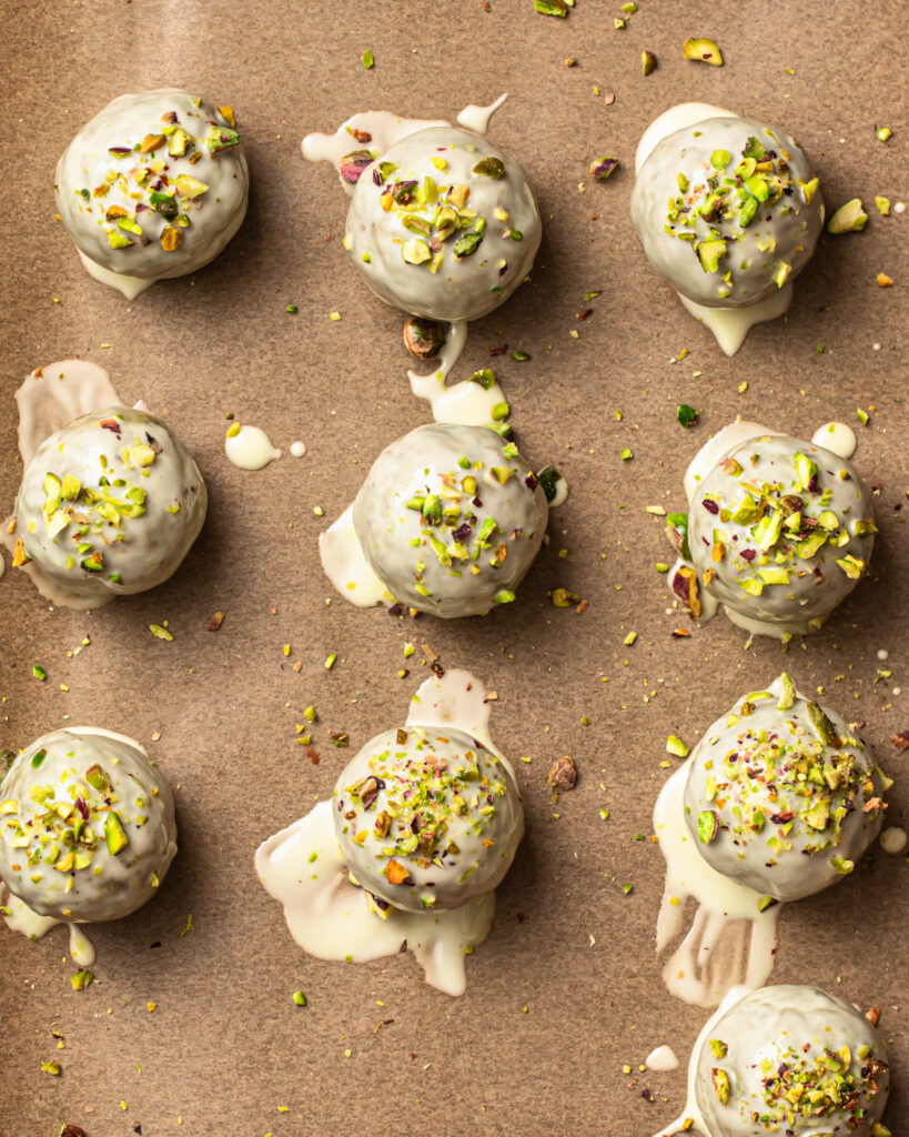 Pistachio protein balls coated in melted white chocolate and topped with finely chopped pistachios. 
