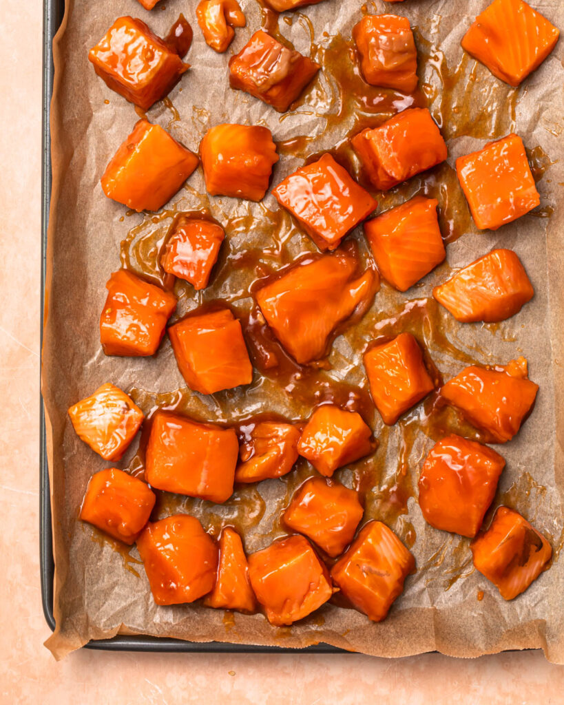 Marinaded salmon cubes spread out on a tray.
