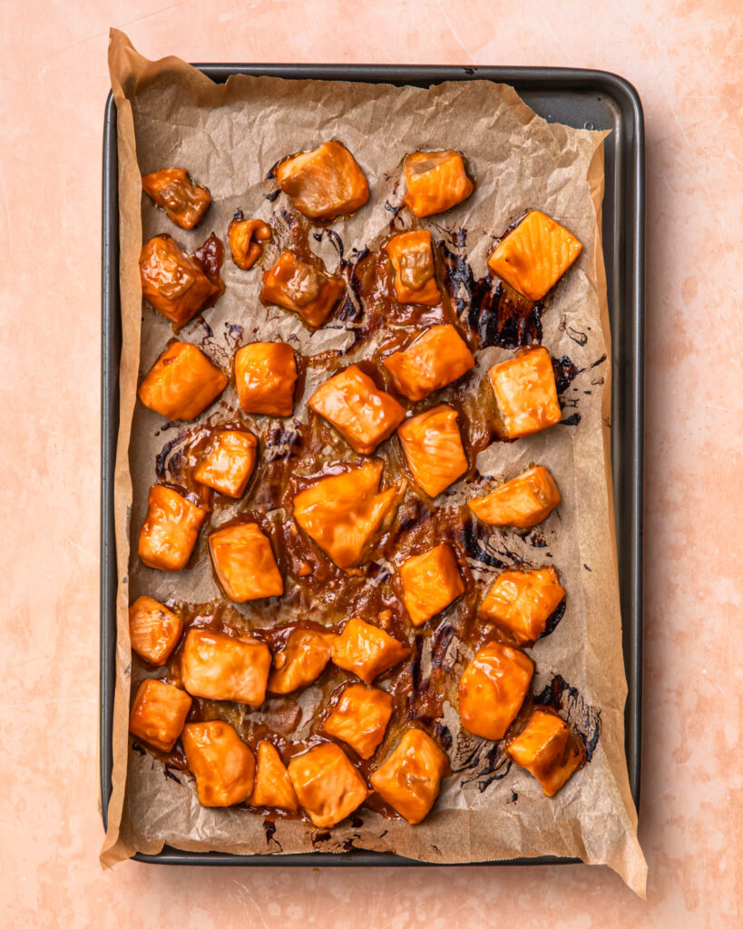 Teriyaki salmon cubes baked on a tray.