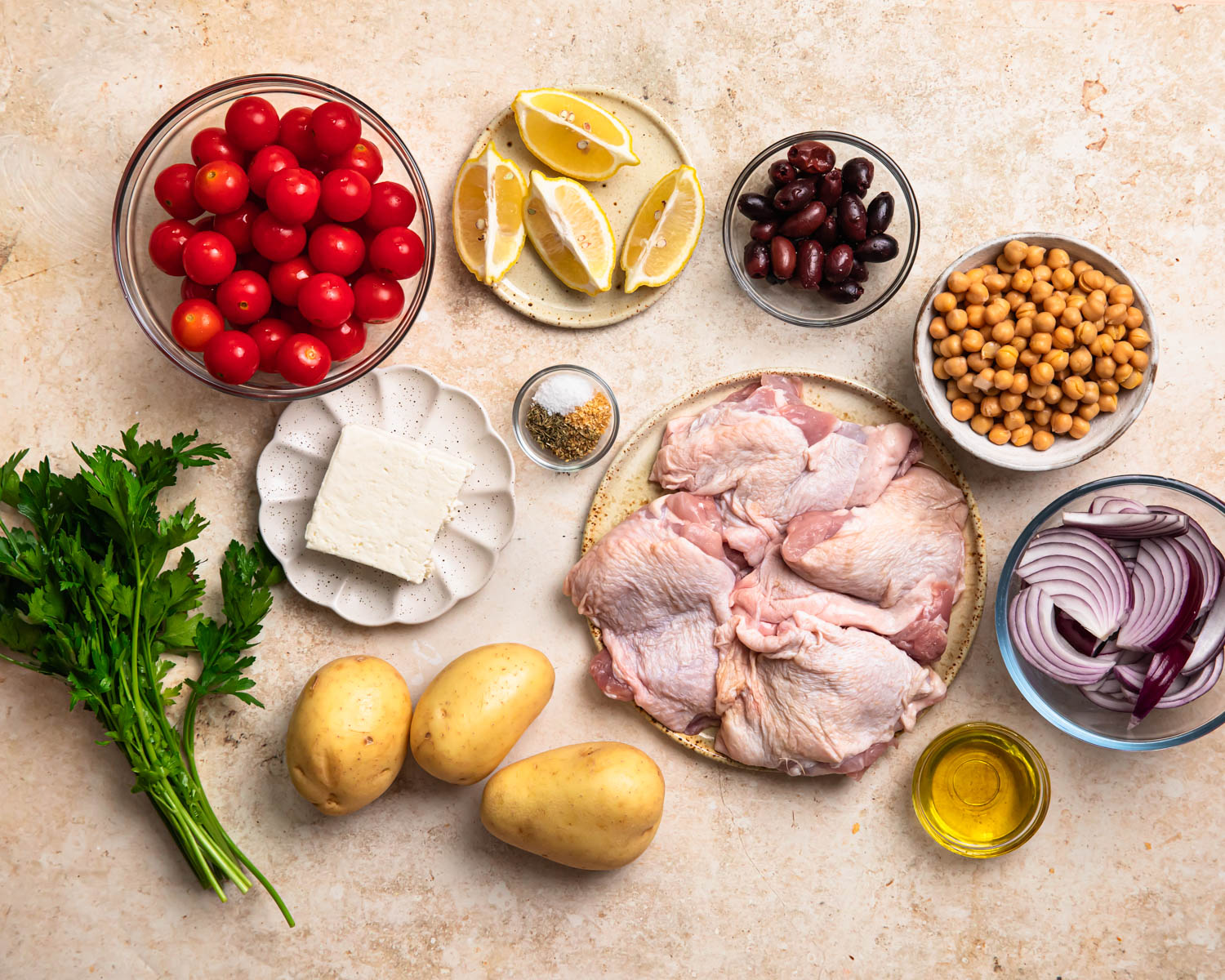 Ingredients to make Mediterranean sheet pan chicken laid out in individual bowls. 