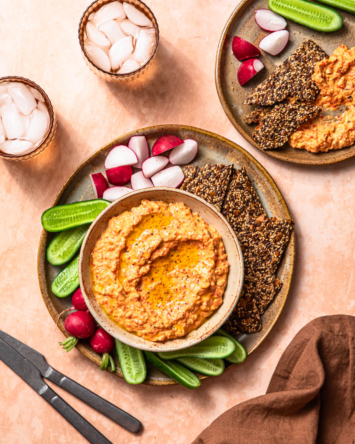 Roasted red pepper and feta dip in a serving bowl alongside vegetable sticks and crackers.