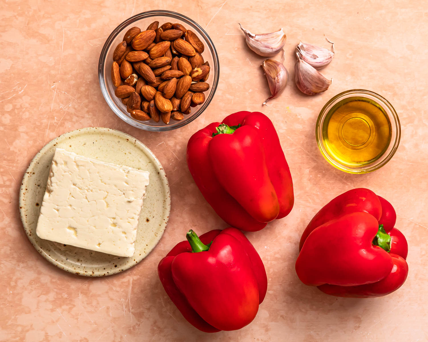 Ingredients to make roasted red pepper feta dip laid out in individual bowls.