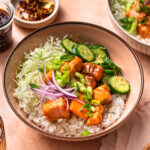 A photo of teriyaki salmon bowls topped with spring onions and red onions.