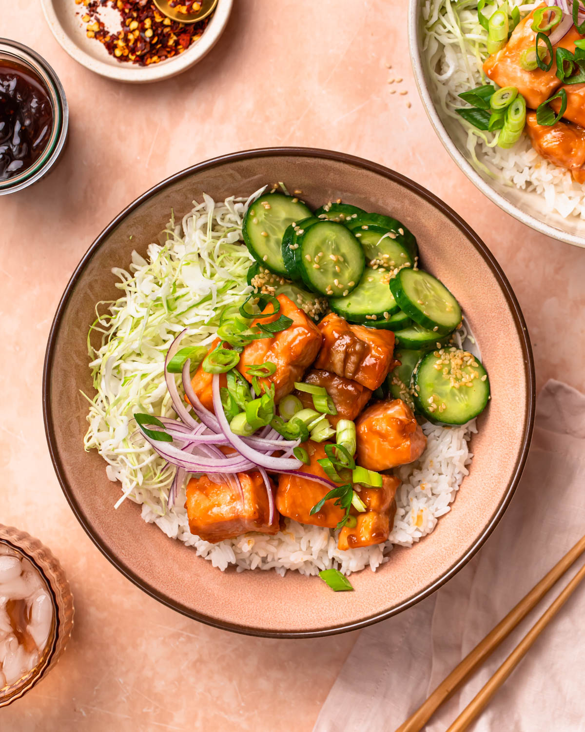 A photo of teriyaki salmon bowls topped with spring onions and red onions.