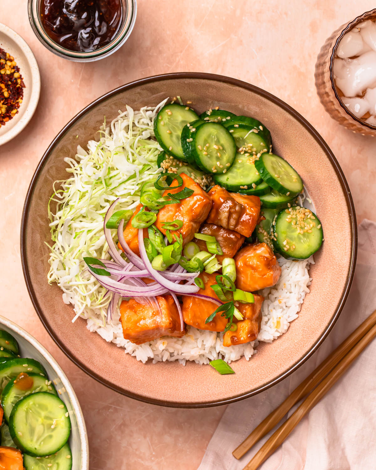 A photo of teriyaki salmon bowls topped with spring onions and red onions.