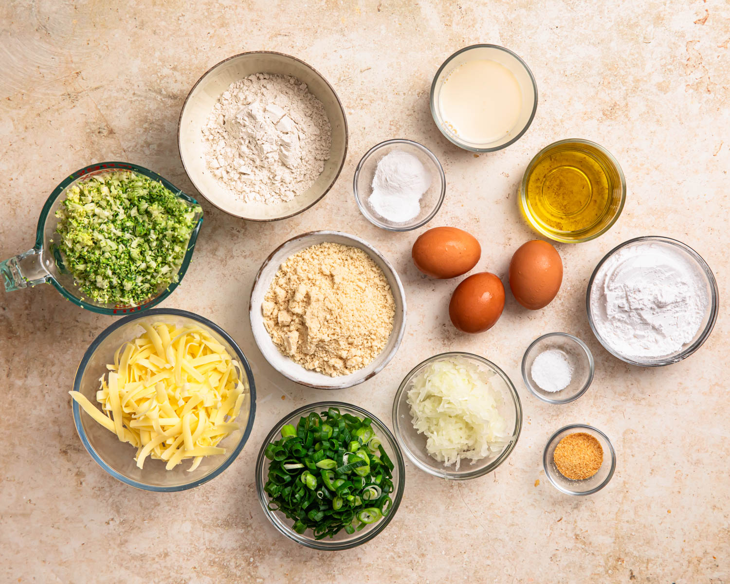 Ingredients for broccoli and cheddar gluten free savoury muffins laid out in individual bowls.