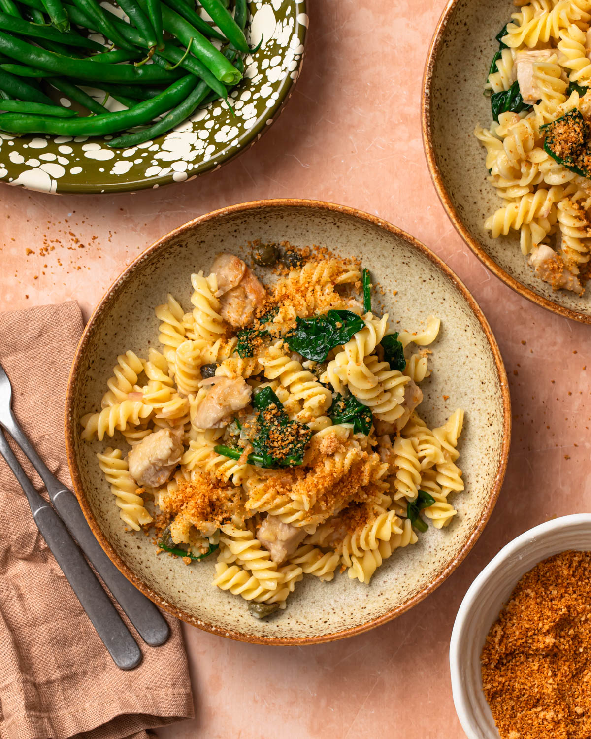 Chicken piccata pasta in a bowl topped with golden brown parmesan breadcrumbs.