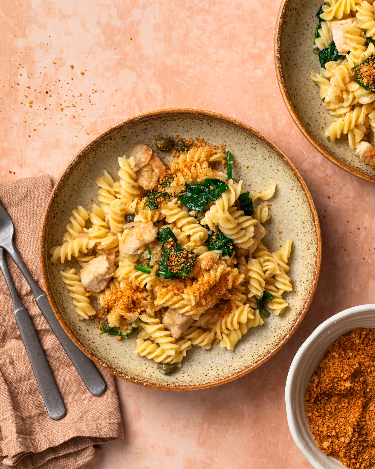 Chicken piccata pasta in a bowl topped with golden brown parmesan breadcrumbs.