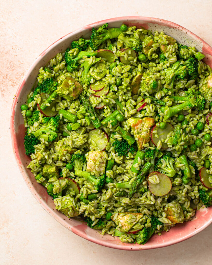 Orzo salad all mixed together in a large salad bowl.