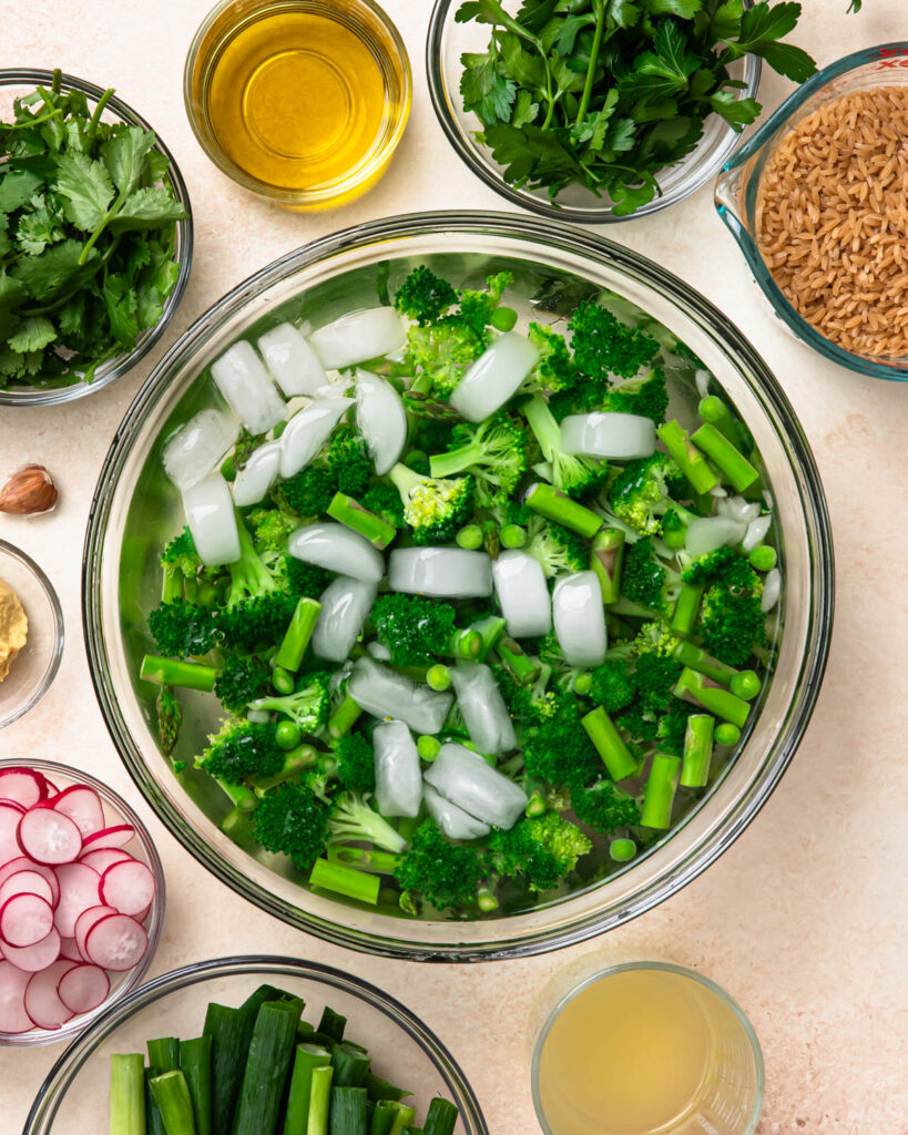 Blanched asparagus, broccoli and peas in an ice bath.