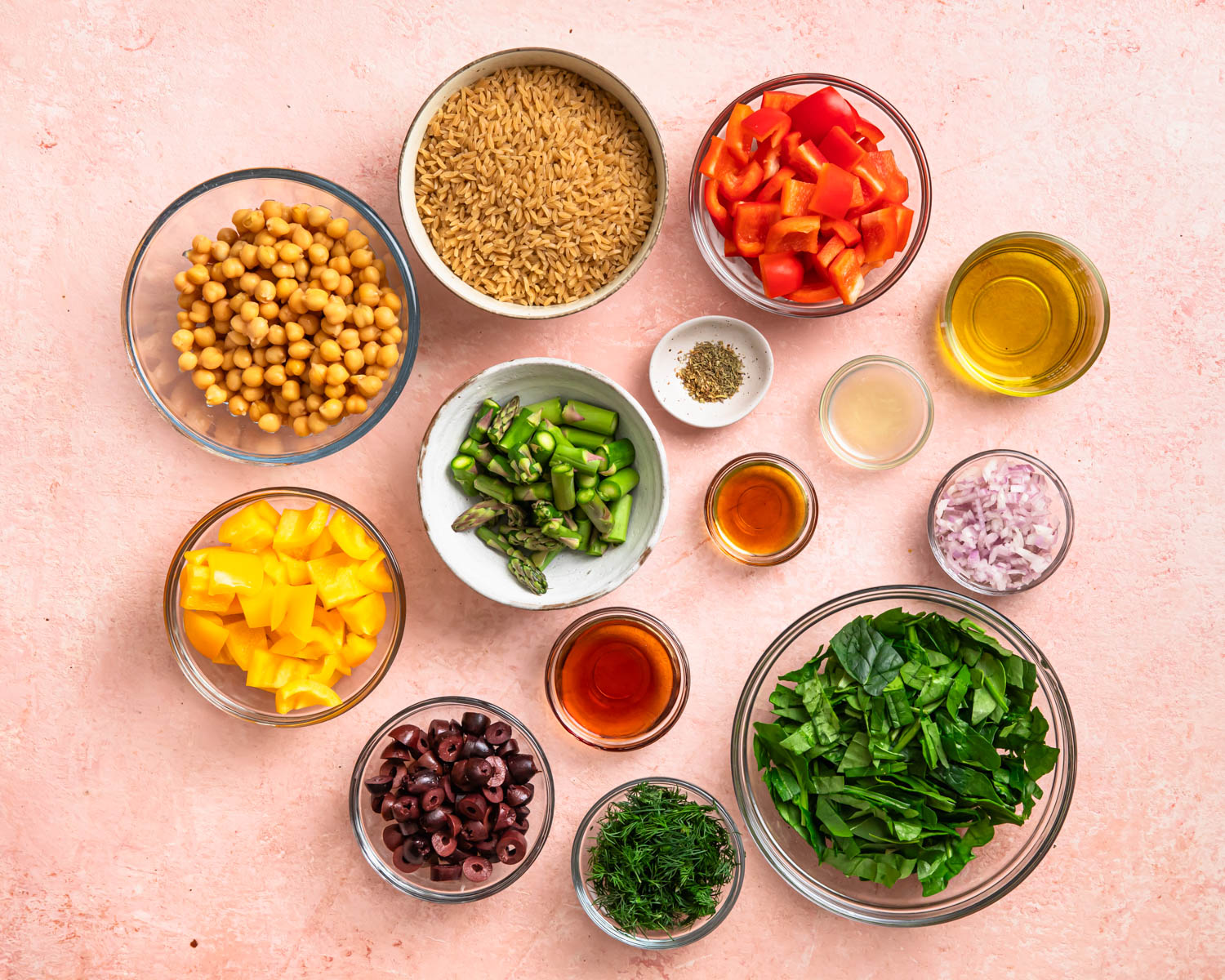 Ingredients for a Mediterranean Orzo Salad laid out in individual bowls.