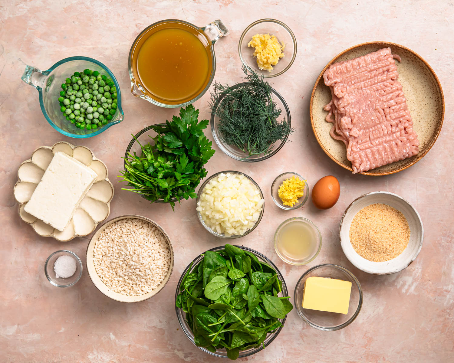 All of the ingredients to make one pan greek chicken meatballs with rice and feta, laid out in individual bowls. 