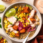 Close up of Tex mex salmon quinoa bowls topped with a wedge of lime and chipotle mayonnaise.